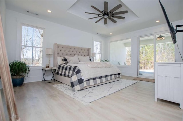 bedroom featuring wood finished floors, a raised ceiling, and recessed lighting