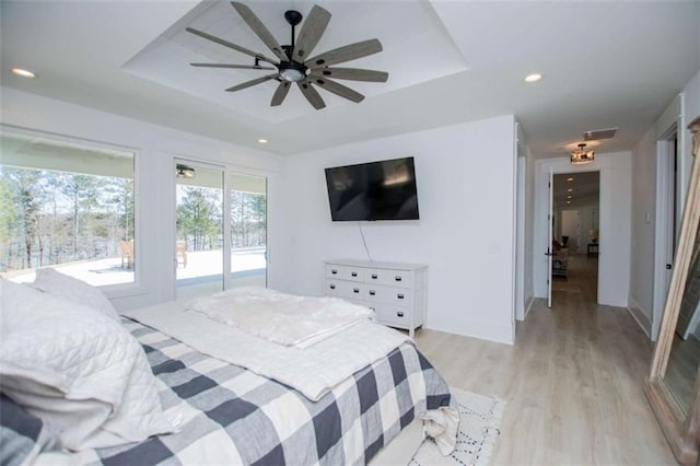 bedroom with a tray ceiling, recessed lighting, visible vents, light wood-style floors, and access to outside