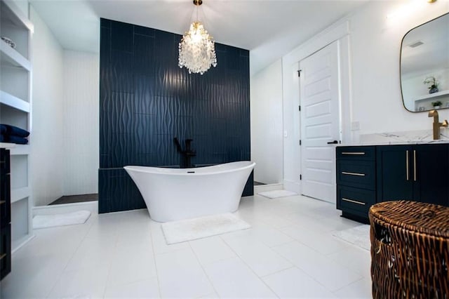 full bathroom with an accent wall, a notable chandelier, a freestanding bath, and vanity