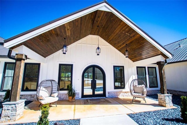 entrance to property with metal roof, french doors, board and batten siding, and a patio area