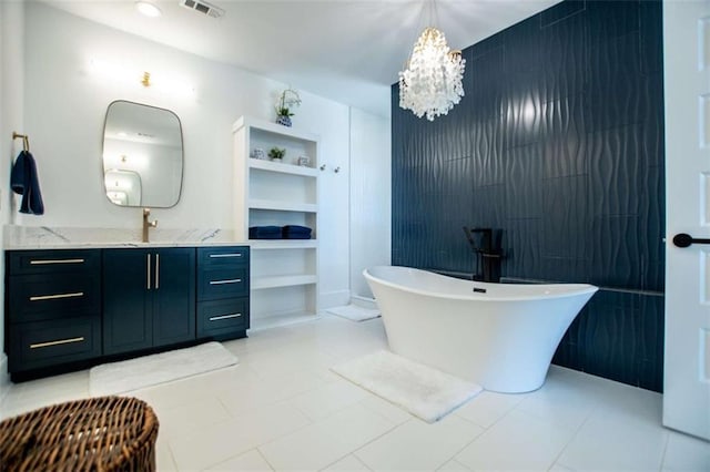 bathroom featuring visible vents, an inviting chandelier, a freestanding bath, vanity, and tile walls