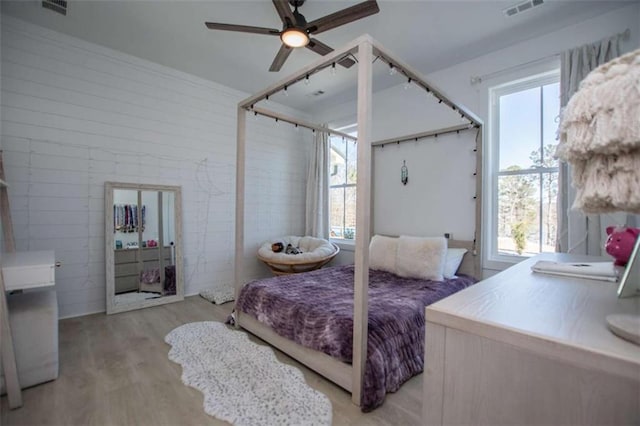 bedroom with light wood-style flooring, visible vents, and ceiling fan