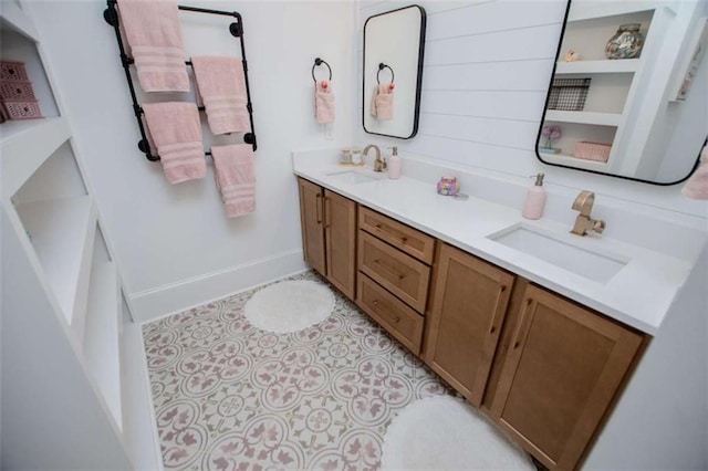 bathroom with double vanity, baseboards, a sink, and tile patterned floors