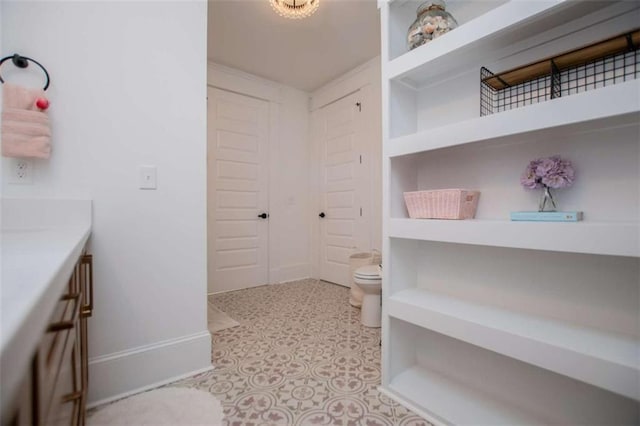 bathroom with baseboards, vanity, and toilet