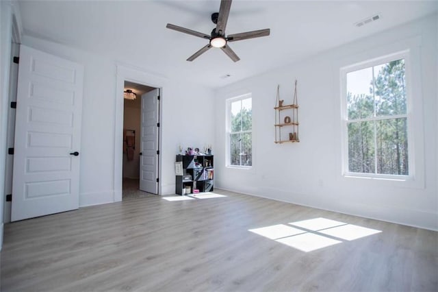 unfurnished bedroom with a ceiling fan, wood finished floors, visible vents, and baseboards