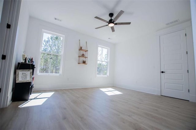 empty room featuring plenty of natural light, wood finished floors, and visible vents