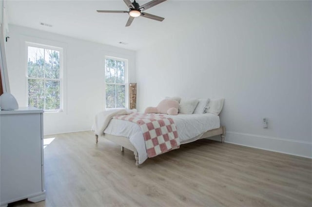 bedroom featuring ceiling fan, light wood-type flooring, visible vents, and baseboards