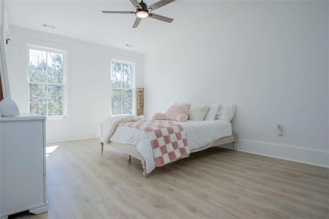 bedroom featuring light wood-type flooring, baseboards, visible vents, and a ceiling fan