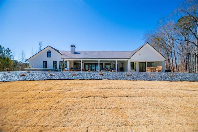 rear view of property featuring metal roof, a yard, and a chimney