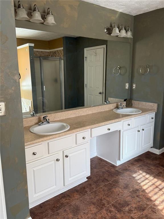 bathroom featuring vanity, a textured ceiling, and walk in shower