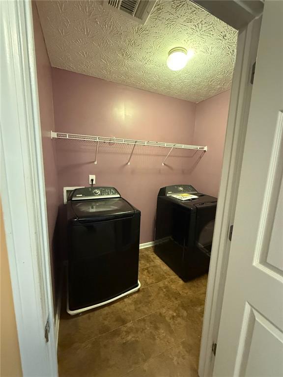 clothes washing area featuring separate washer and dryer and a textured ceiling