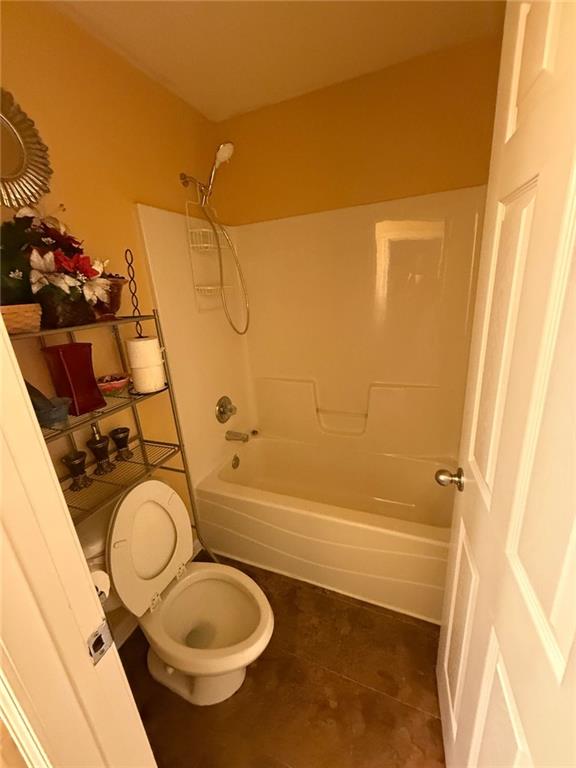 bathroom with tile patterned floors, toilet, and washtub / shower combination