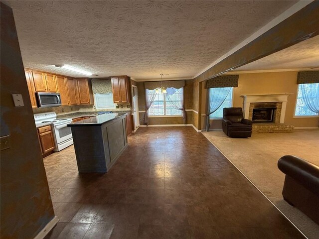 kitchen featuring a textured ceiling, a healthy amount of sunlight, electric stove, and hanging light fixtures