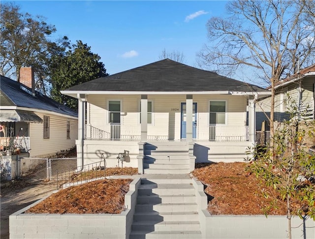 bungalow featuring a porch, roof with shingles, and fence