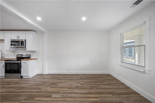 kitchen with stainless steel appliances, butcher block counters, dark wood-type flooring, white cabinetry, and baseboards