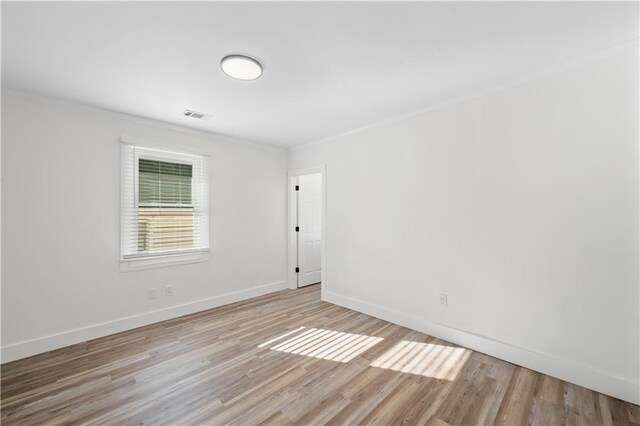 empty room with visible vents, baseboards, and wood finished floors