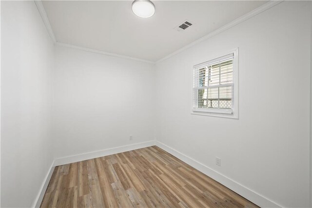 spare room with baseboards, visible vents, crown molding, and wood finished floors