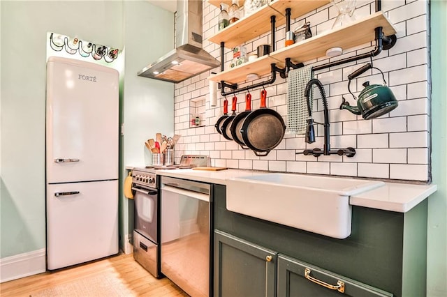 kitchen featuring stainless steel appliances, light hardwood / wood-style flooring, tasteful backsplash, and wall chimney exhaust hood