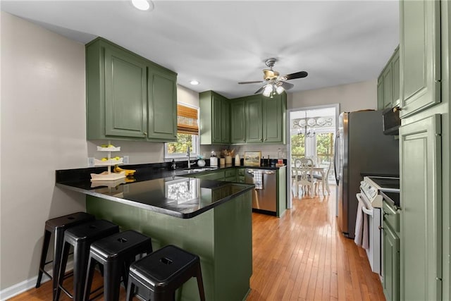 kitchen with green cabinets, electric stove, a sink, a wealth of natural light, and a peninsula