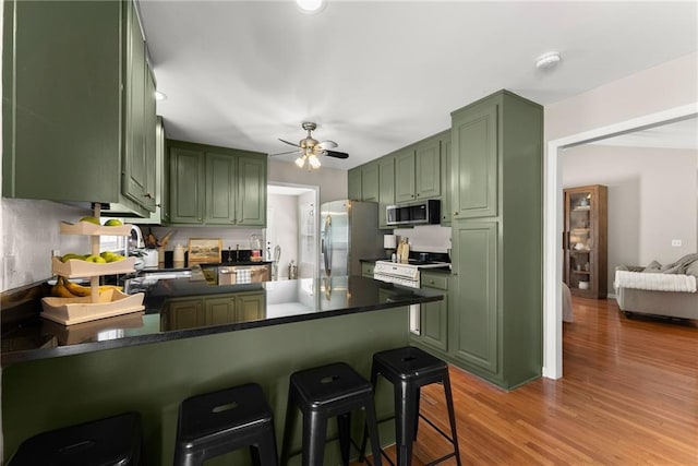 kitchen featuring green cabinetry, a sink, appliances with stainless steel finishes, a peninsula, and ceiling fan