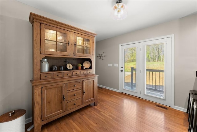 bar with baseboards, light wood-style floors, and visible vents