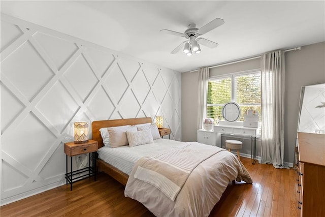 bedroom with ceiling fan, a decorative wall, hardwood / wood-style flooring, and an accent wall