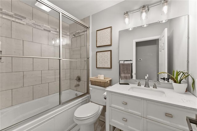 bathroom with combined bath / shower with glass door, toilet, and vanity