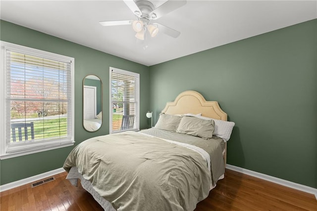 bedroom with baseboards, ceiling fan, visible vents, and hardwood / wood-style floors