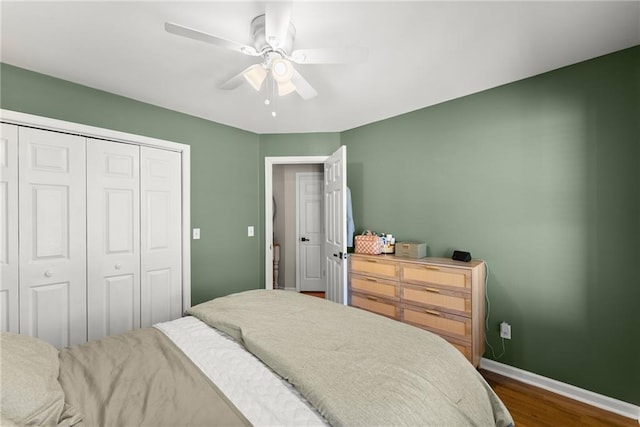 bedroom featuring a closet, baseboards, dark wood-type flooring, and a ceiling fan