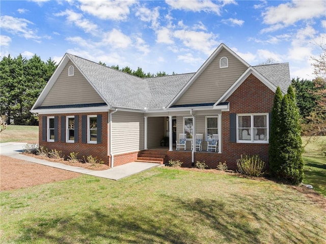 view of front facade with brick siding, a shingled roof, a front lawn, and a porch