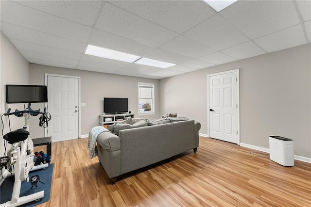 living area with baseboards, light wood-style floors, and a paneled ceiling