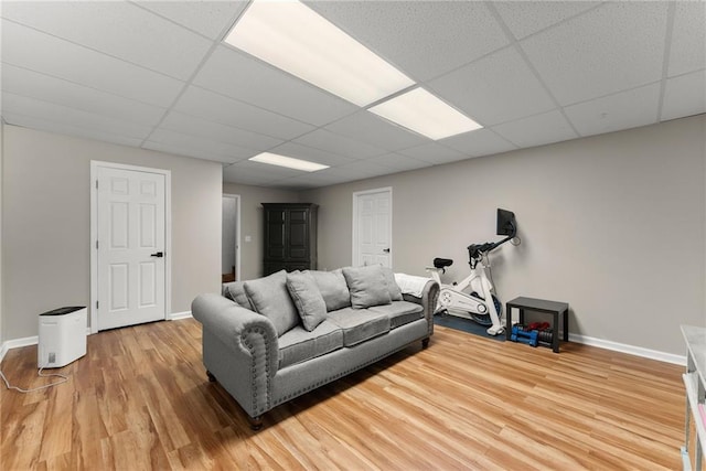 living room with a paneled ceiling, baseboards, and light wood-type flooring