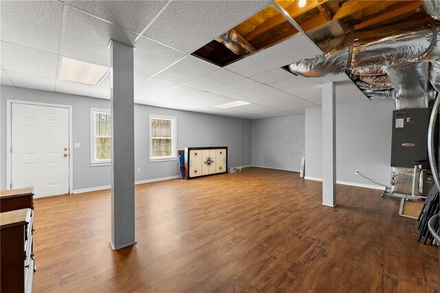 basement with baseboards, wood finished floors, and a drop ceiling