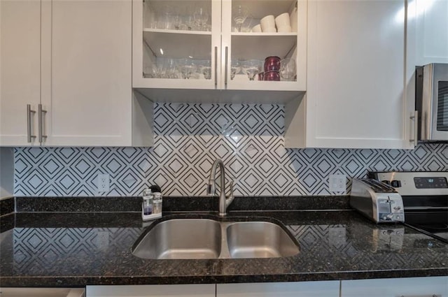 2657 Lenox Rd Unit C30, Atlanta, GA 30324 - kitchen with dark stone countertops, a sink, glass insert cabinets, and white cabinets