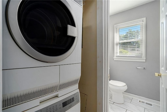 clothes washing area with light tile patterned flooring and stacked washing maching and dryer