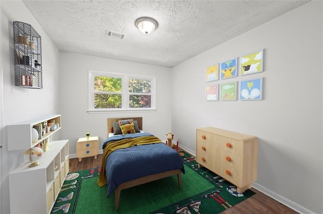 bedroom with a textured ceiling and dark hardwood / wood-style flooring