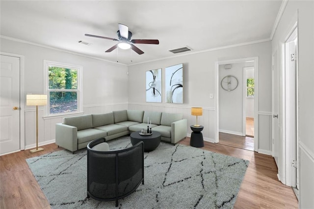 living room with light hardwood / wood-style flooring, ceiling fan, and crown molding