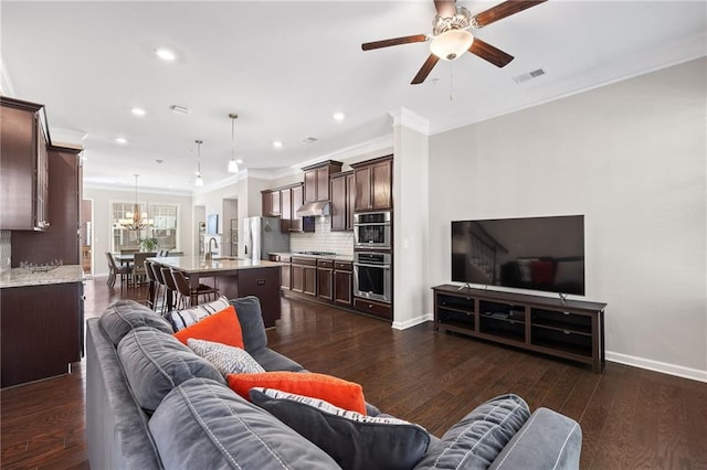 living room featuring ceiling fan with notable chandelier, crown molding, dark hardwood / wood-style flooring, and sink