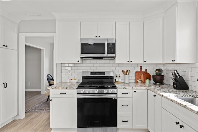 kitchen with white cabinets, backsplash, and appliances with stainless steel finishes