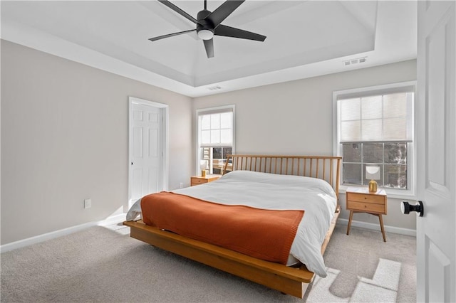 carpeted bedroom featuring ceiling fan and a raised ceiling