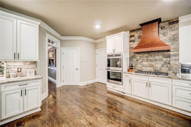 kitchen with custom range hood, white cabinetry, appliances with stainless steel finishes, and dark wood-type flooring