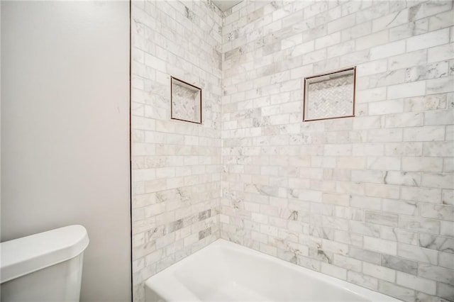 bathroom featuring toilet and tiled shower / bath combo