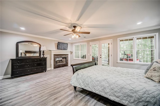 bedroom featuring access to exterior, a fireplace, ceiling fan, and hardwood / wood-style flooring