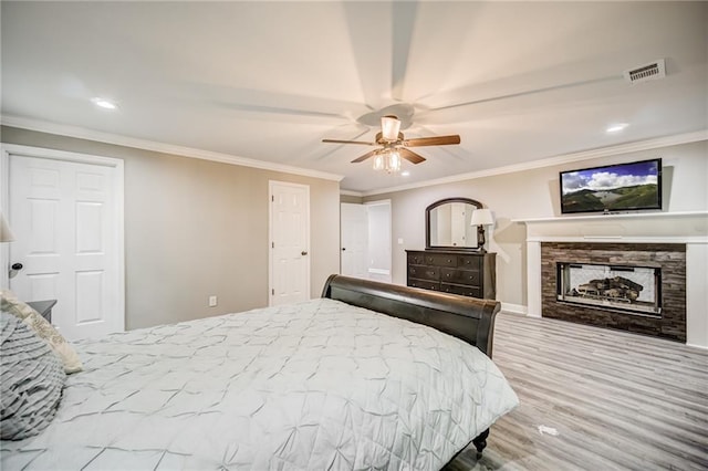 bedroom with a multi sided fireplace, crown molding, ceiling fan, and light wood-type flooring