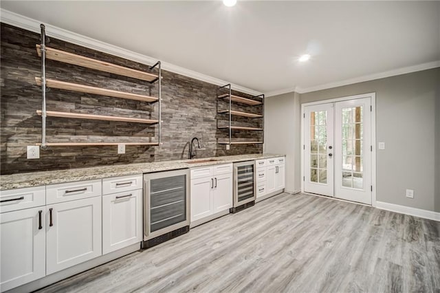 interior space with light wood-type flooring, french doors, white cabinetry, and beverage cooler