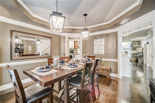 dining space featuring dark hardwood / wood-style flooring, ornamental molding, and a tray ceiling