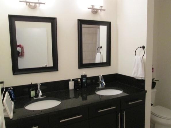 bathroom featuring double vanity, a sink, and toilet