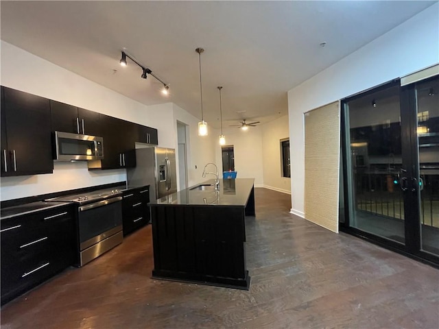 kitchen featuring dark countertops, appliances with stainless steel finishes, dark cabinets, pendant lighting, and a sink