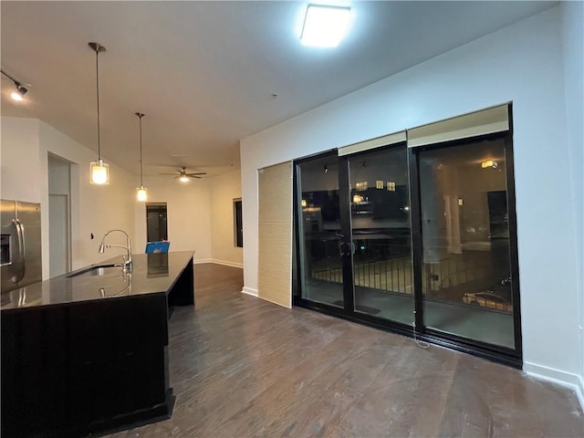 kitchen featuring dark wood-style flooring, decorative light fixtures, a sink, ceiling fan, and an island with sink