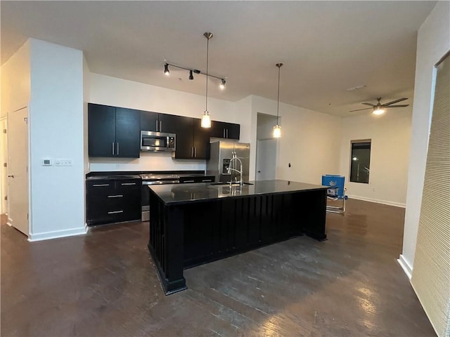 kitchen featuring decorative light fixtures, stainless steel appliances, dark countertops, a sink, and dark cabinetry